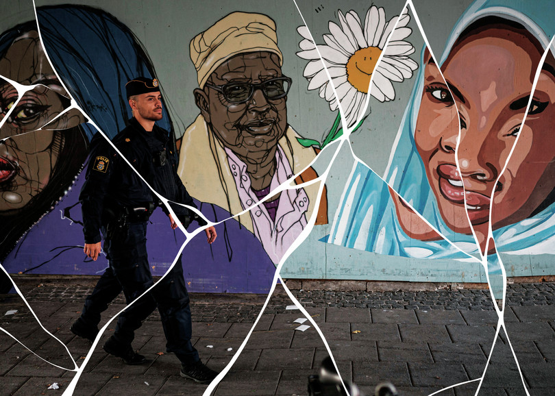 A police officer on patrol walks past a mural depicting immigrants in Rinkeby, Sweden.
